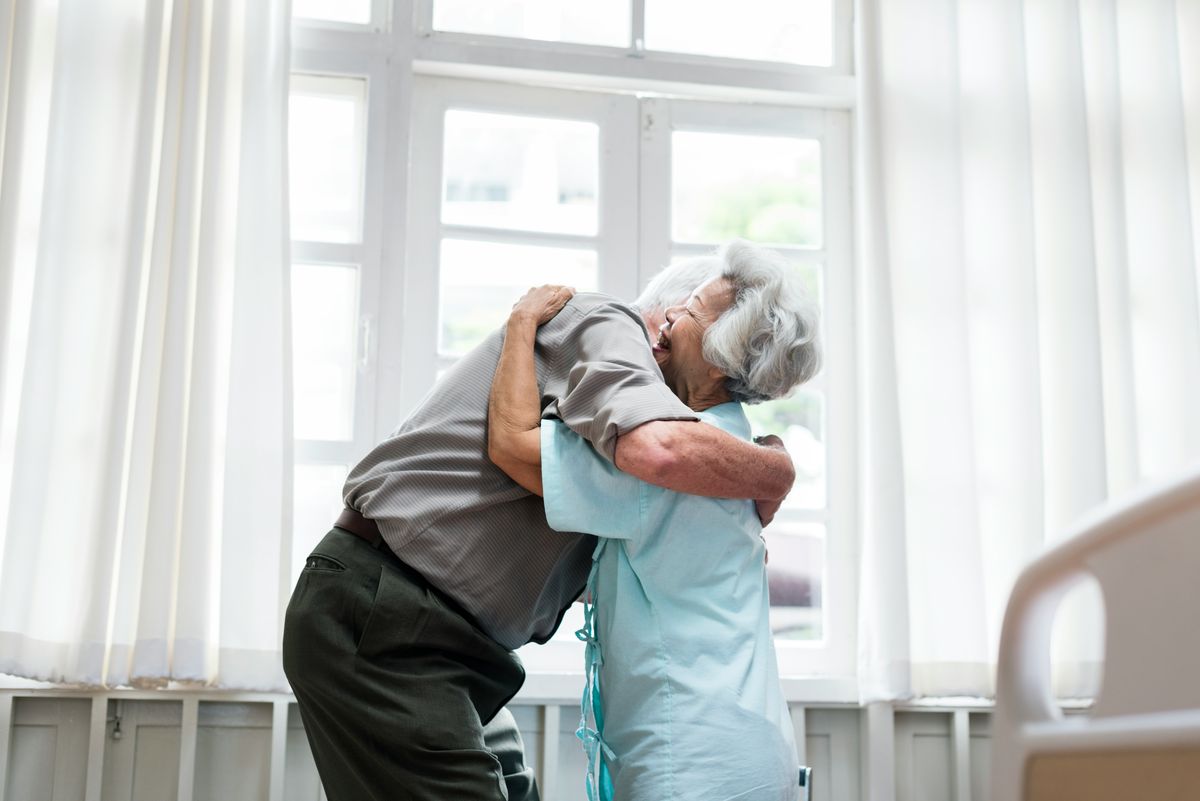 Man giving elderly lady a hug