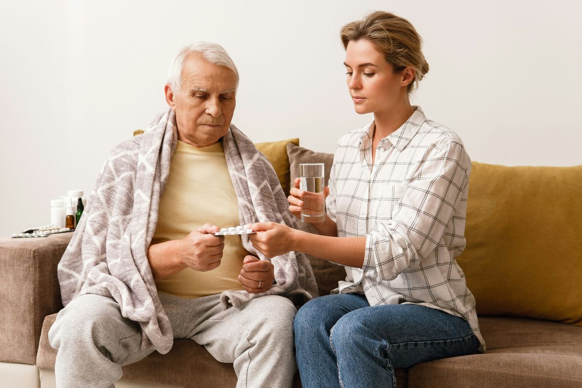 Caregiver giving elderly medication