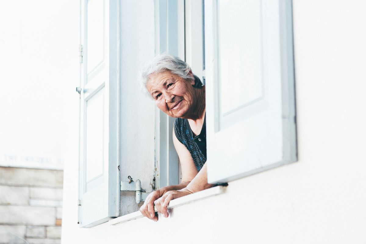 Elderly lady looking out the window alone